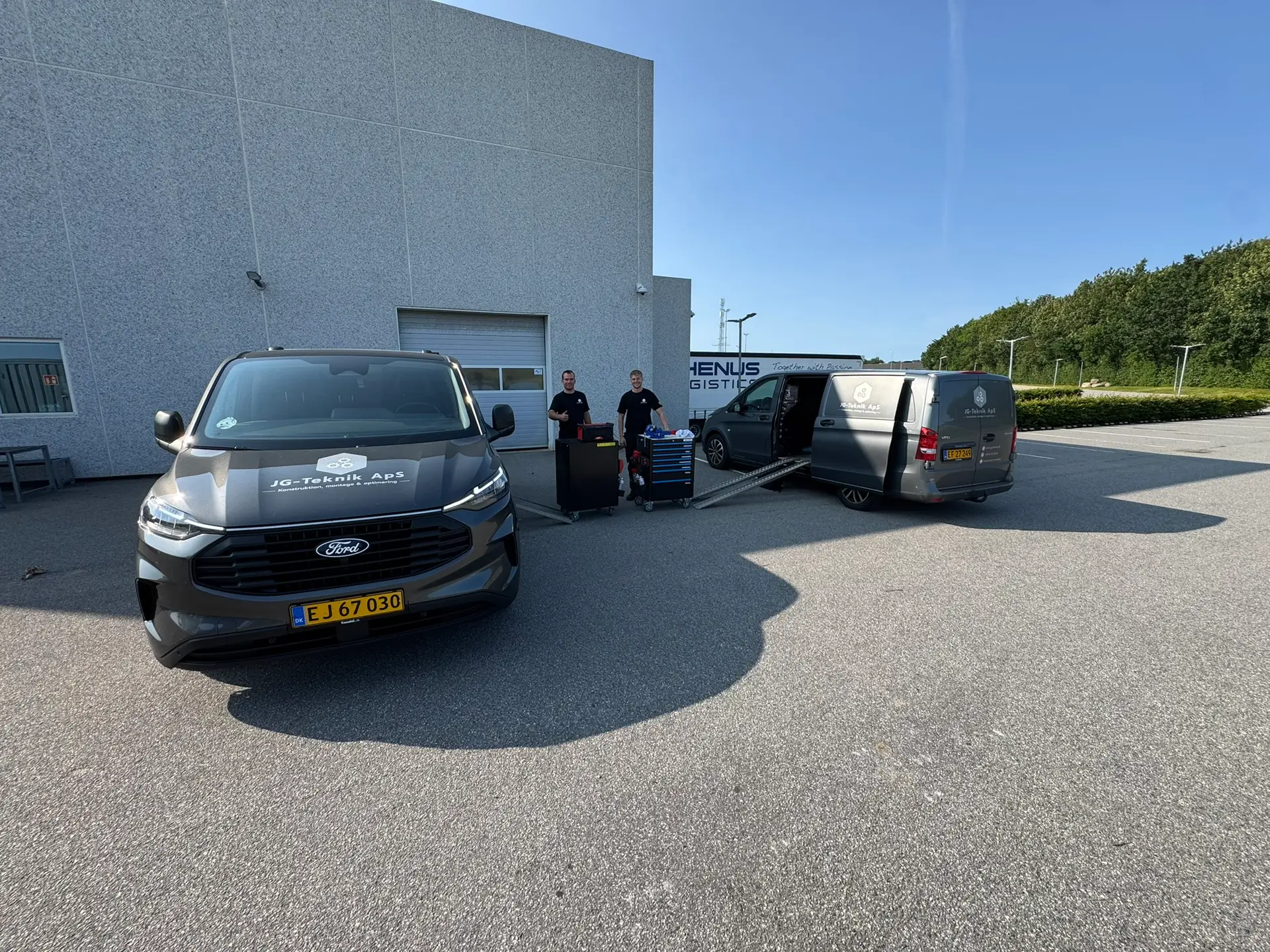 JG Tekniks servicebiler og medarbejdere ved en industribygning