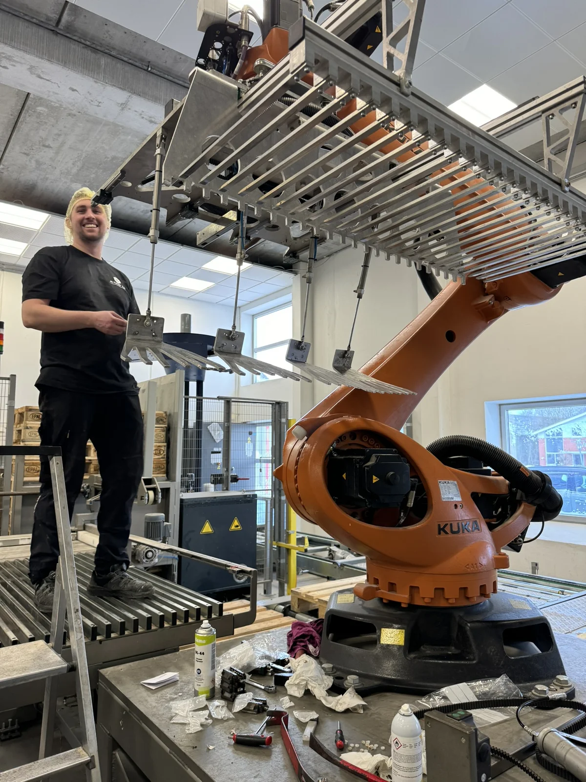 Medarbejder ved en KUKA-industrirobot med gribeværktøj